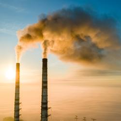 Factory towers with pollution smoke against sunset.