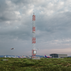 AWS810 pictured at airport with plane flying in the background.