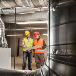 Workers making final touches to HVAC system. HVAC system stands for heating, ventilation and air conditioning technology.