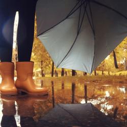 Feet in rubber boots rain puddle city