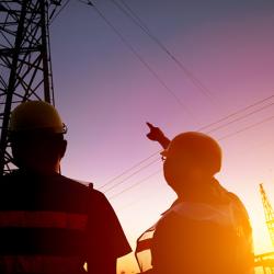 Two worker watching the power tower and substation with sunset background