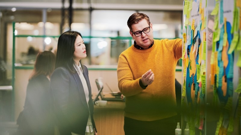 Two colleagues workshopping by a whiteboard